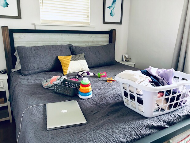 Laundry, Mac, and baby toys on bed