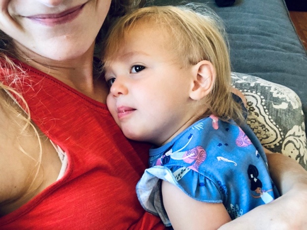 Toddler snuggling with mom on couch