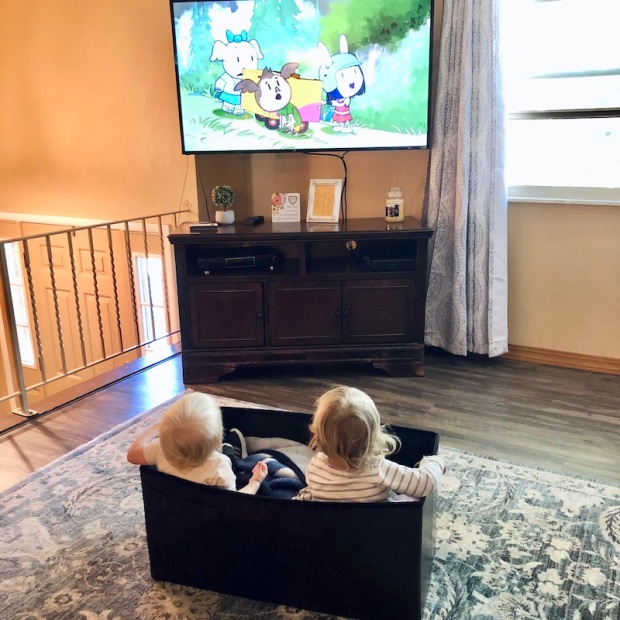 Toddlers sitting in a box watching TV