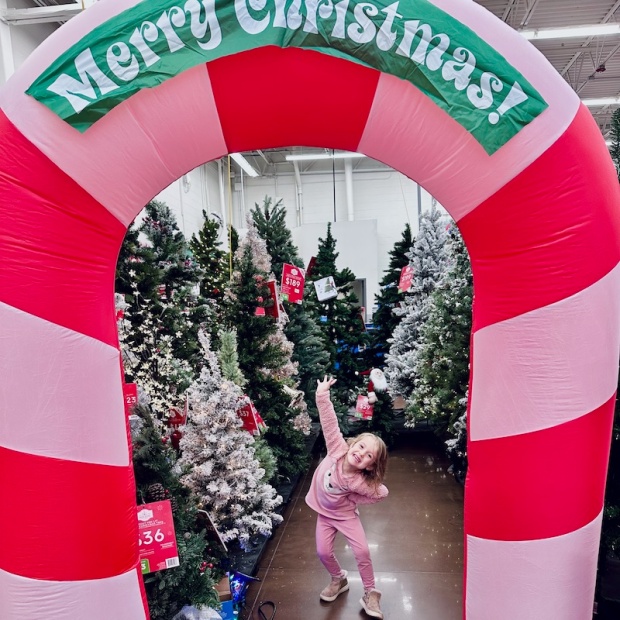 Girl standing by Christmas tree display in Walmart
