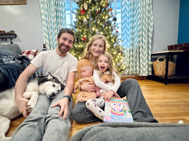 Family Christmas picture with baby and four year old and husky in front of Christmas tree
