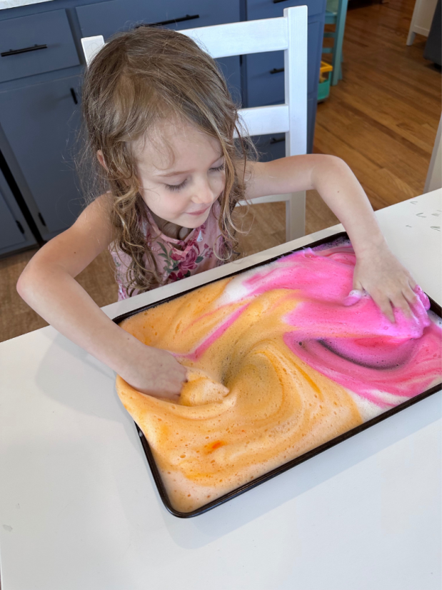 Girl playing with tray of pink and orange foam